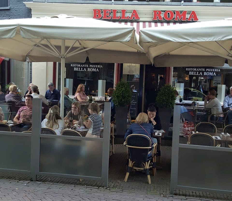 Gasten op het terras aan de Brink onder de parasols