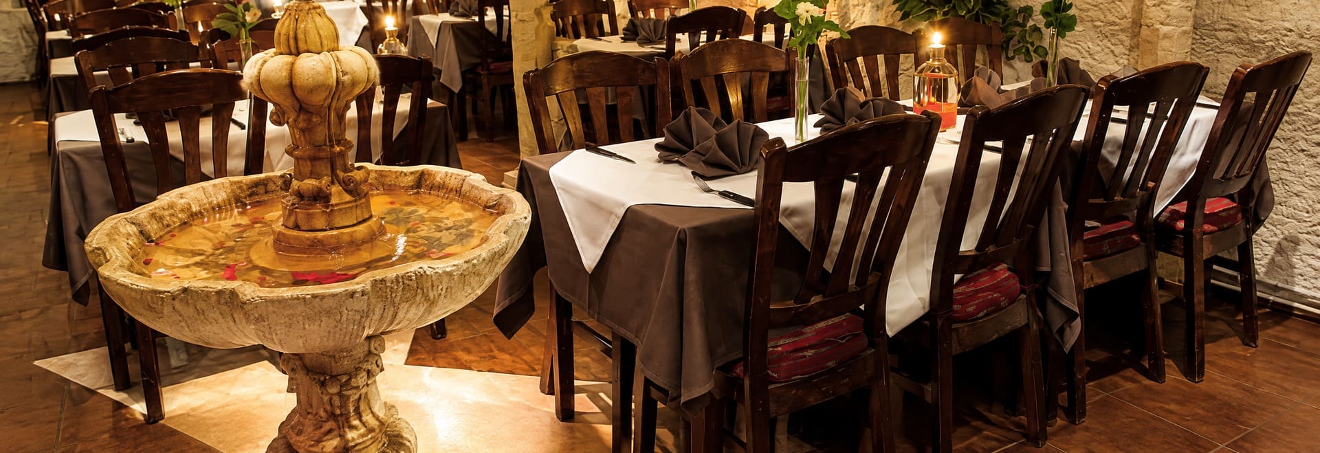 De stenen fontein midden in de zaal, met gedekte tafels eromheen