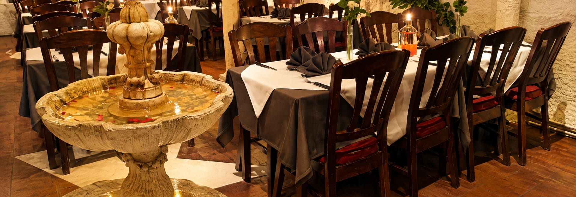 De fontein en een gedekte tafel in de zaal van Bella Roma